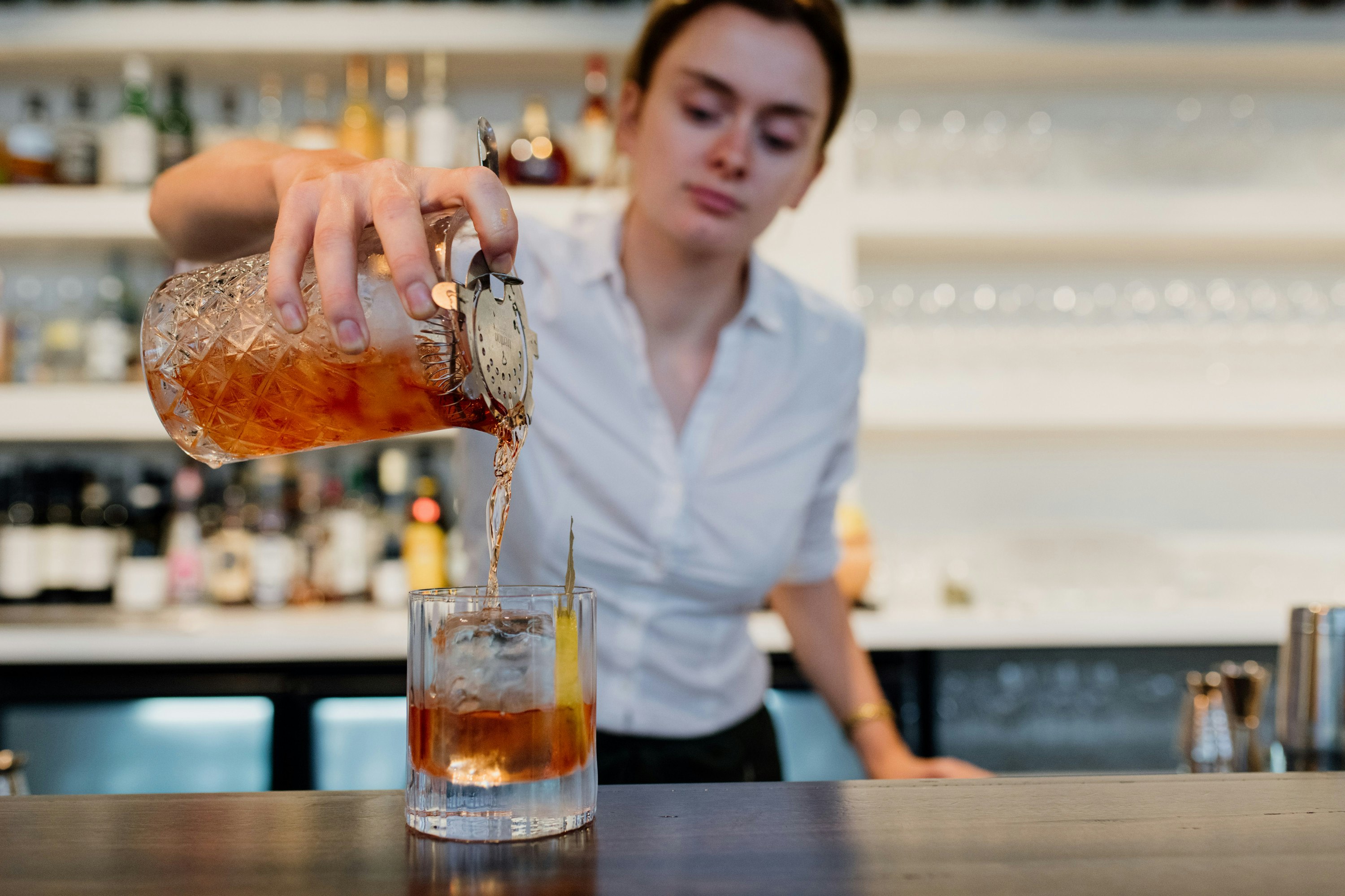 a bartender pouring a drink into a glass